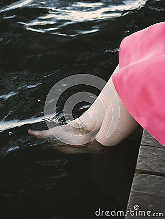 Unrecognizable girl dipping bare feet in water Stock Photo