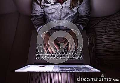 Unrecognizable girl, sitting in a dark, playing with laptop Stock Photo