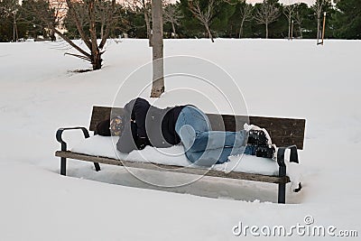 Unrecognizable homeless man sleeping on bench in snowy cold winter Stock Photo