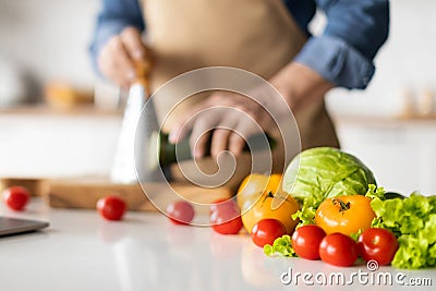 Unrecognizable Man In Apron Cooking Vegetable Meal In Kitchen Stock Photo