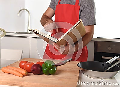 Unrecognizable man in apron at kitchen following recipe book healthy cooking Stock Photo