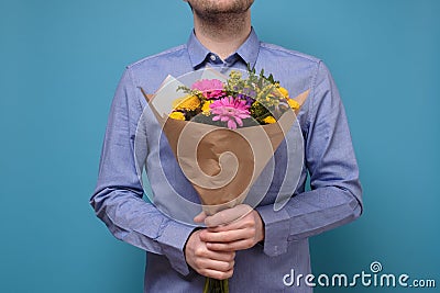 Unrecognizable man in blue hirt holding flowers as gift for his mother Stock Photo