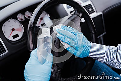 Unrecognizable man in a car using alcohol gel to disinfect steering wheel during pandemic coronavirus covid-19 Stock Photo