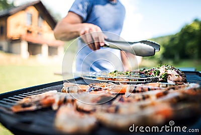 Unrecognizable man cooking seafood on a barbecue grill in the backyard. Stock Photo