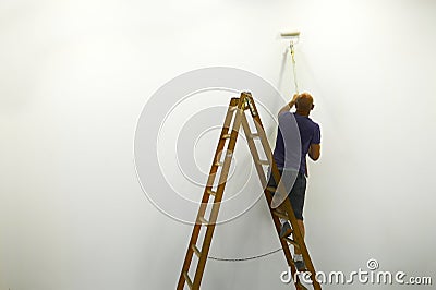 Unrecognizable man on ladder back view paints white wal Editorial Stock Photo