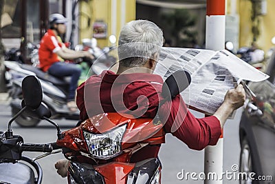 unrecognizable man in red shirt reads newspaper, sits on the sco Editorial Stock Photo
