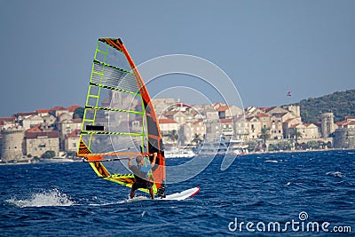 Unrecognizable man windsurfs past the ancient old town of Korcula, Croatia. Stock Photo