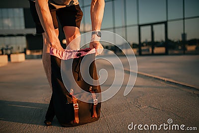 Unrecognizable model pulls something out of a backpack. Gray clothing in trendy minimalistic style. Street fashion for Stock Photo