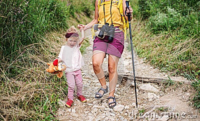 Unrecognizable mother with small crying daughter hiking outdoors in summer nature. Stock Photo