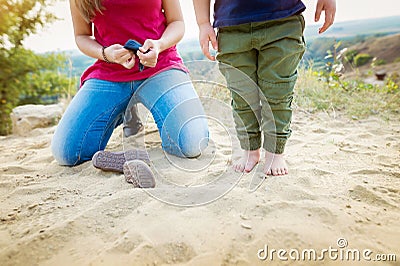 Unrecognizable mother with son on sand beach at the lake. Stock Photo