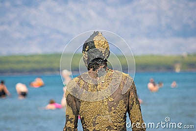 Unrecognizable person in healthy mud on beach Editorial Stock Photo