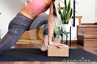 Unrecognizable woman doing yoga twist at home with help of cork yoga block. Stock Photo