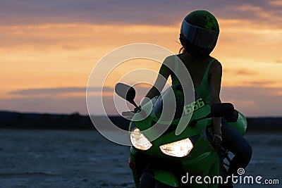 Unrecognizable woman on motorcycle at sunset Stock Photo