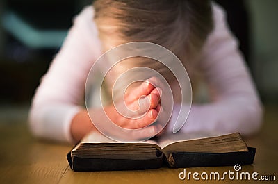 Unrecognizable woman praying, hands clasped together on her Bibl Stock Photo
