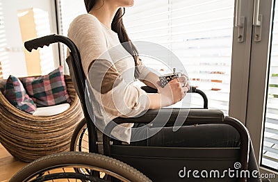 Unrecognizable young disabled woman in wheelchair at home. Stock Photo