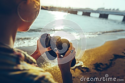 Unrecognizable Young Girl Standing On The Shore And Holding Binoculars. Scout Wanderlust Travel Concept Stock Photo