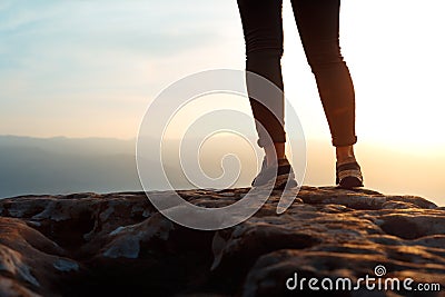 Unrecognizable young success woman hiker legs on mountain peak rock, rear view. Concept achieving goal, beginning of the path, Stock Photo