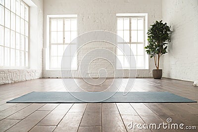 Unrolled yoga mat on wooden floor in yoga studio Stock Photo