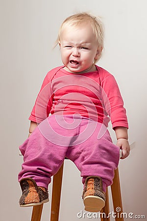 Unsatisfied young baby sit on chair Stock Photo