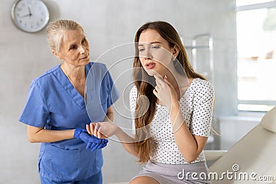 Unsatisfied young woman looking in the mirror sitting on clinical chair Stock Photo