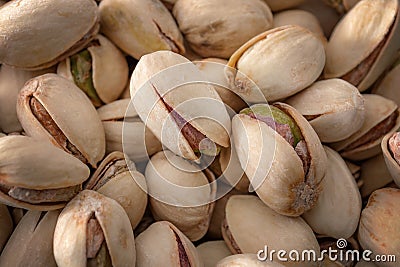 Unshelled nuts and healthy vegetarian foods close up on a pile of roasted and salted pistachios in shell texture, background Stock Photo