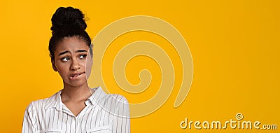 Unsure Afro Girl Looking Aside At Copy Space Over Yellow Background Stock Photo