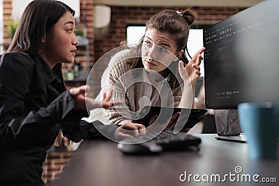 Unsure asian programming expert asking colleague about generated bug report file. Stock Photo