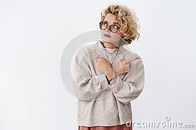 Unsure and hesitant cute questioned hipster female wearing glasses and makeup raising eyebrow doubtful looking Stock Photo