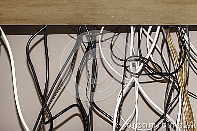 Untidy cables hanging behind a computer desk Stock Photo