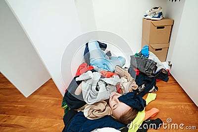 Untidy clutter clothing closet. Boy with messy stack of clothes things on floor. Home chores housework Stock Photo