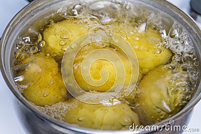 Untreated potatoes boil in a pot on a gas stove. Stock Photo