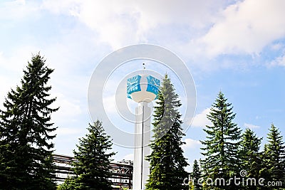 Unusual clock on a background of a white-blue sky. A clock in the form of a molecule, an atom. chemical production, a watch-column Stock Photo