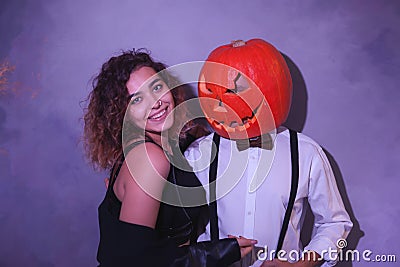 Unusual couple at Halloween party, Woman with pumpkin on head Stock Photo