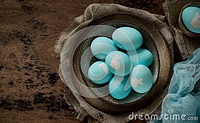 Unusual Easter on dark old background. Ceramic brown bowl with blue eggs with rabbit Stock Photo