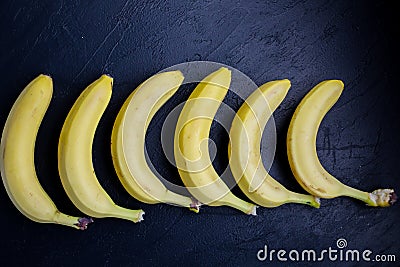 Unusual and fresh photo of bananas lying in a row on black background. Stylish Stock Photo