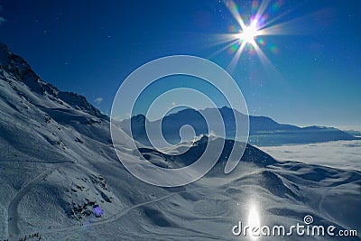 Unusual halo light effect, the sun reflects off the snow and creates a bright pillar of light high in the mountains Stock Photo