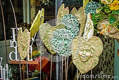 Unusual handmade clay fairy and Greenman garden stakes on display in the springtime Stock Photo