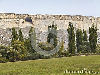 Unusual landscape with green meadow and trees against the background of the famous sight of the Crimea of the white mountains of A Stock Photo