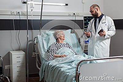 Unwell senior woman patient laying in hospital bed Stock Photo