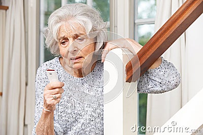 Unwell Senior Woman Using Personal Alarm At Home Stock Photo