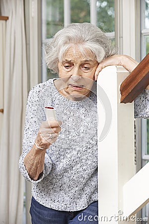 Unwell Senior Woman Using Personal Alarm At Home Stock Photo