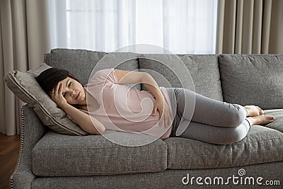 Unhealthy pregnant woman lying on sofa having pain Stock Photo