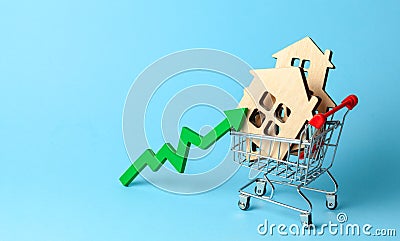 Up arrow and houses in shopping cart on blue background. Market growth in real estate prices Stock Photo