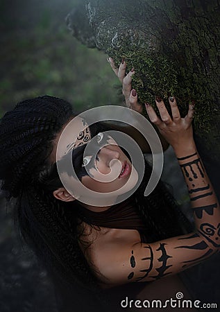 An up close portrait of a wild Amazon girl. Shaman girl with long black hair and ritual makeup Stock Photo