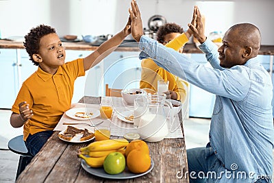 Upbeat single-parent family high-fiving each other at breakfast Stock Photo