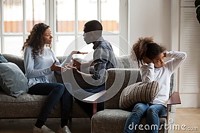 Upset african daughter closing ears while parents fighting at ho Stock Photo