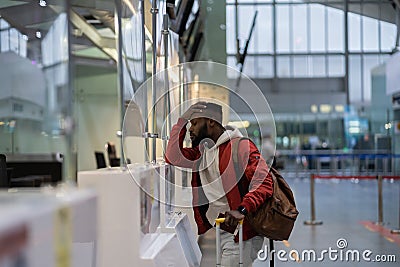 Upset African student guy in airport feeling uncertain about moving to another country Stock Photo