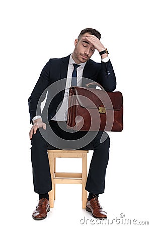 Upset businessman holding briefcase and hand on head, thinking Stock Photo