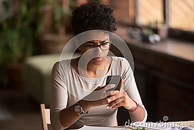 Upset confused african woman holding cellphone having problem with phone Stock Photo