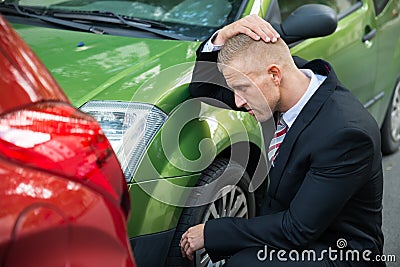 Upset driver looking at car after traffic collision Stock Photo